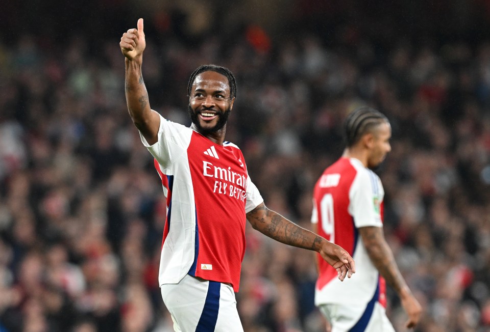 a soccer player wearing a red emirates jersey giving a thumbs up