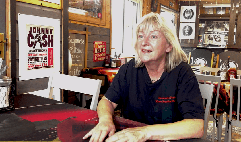 a woman sits at a table in front of a johnny cash poster