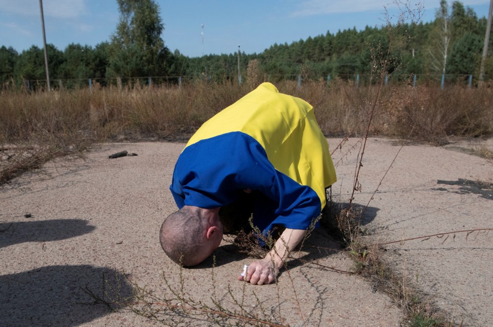 a man in a blue and yellow shirt is kneeling on the ground