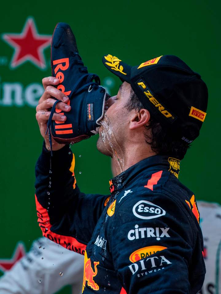 a man wearing a red bull hat is drinking from a shoe