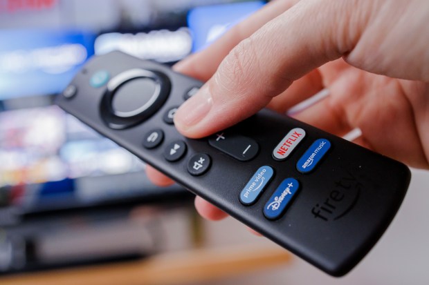 a person is holding a fire tv remote with netflix and amazon music buttons