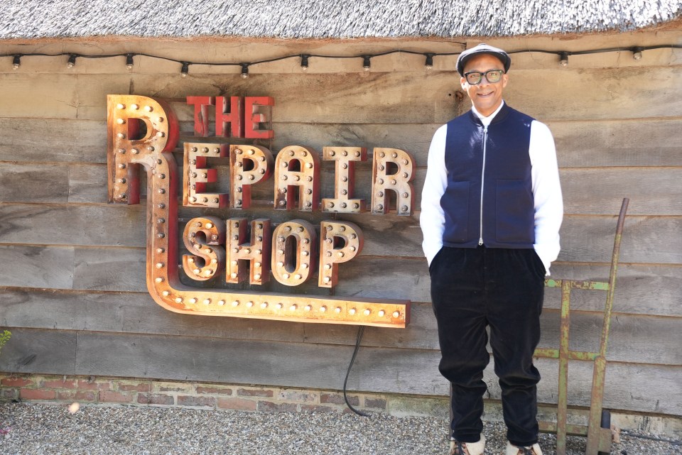 a man stands in front of a sign that says the repair shop