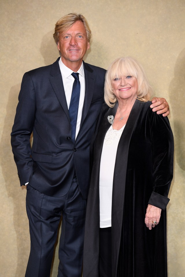 a man in a suit and tie stands next to a woman in a black coat