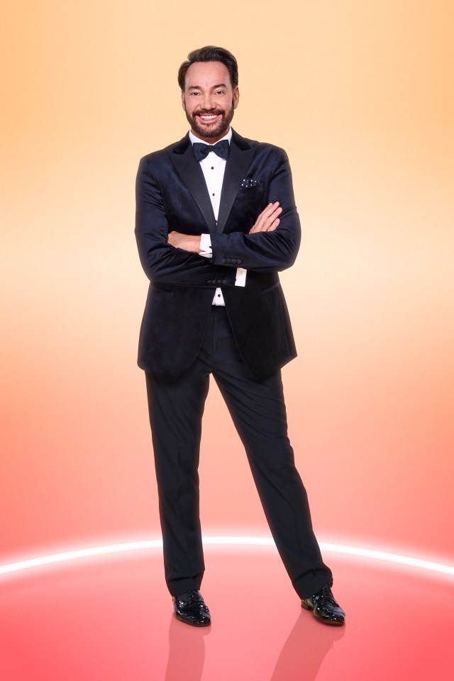 a man in a tuxedo stands with his arms crossed