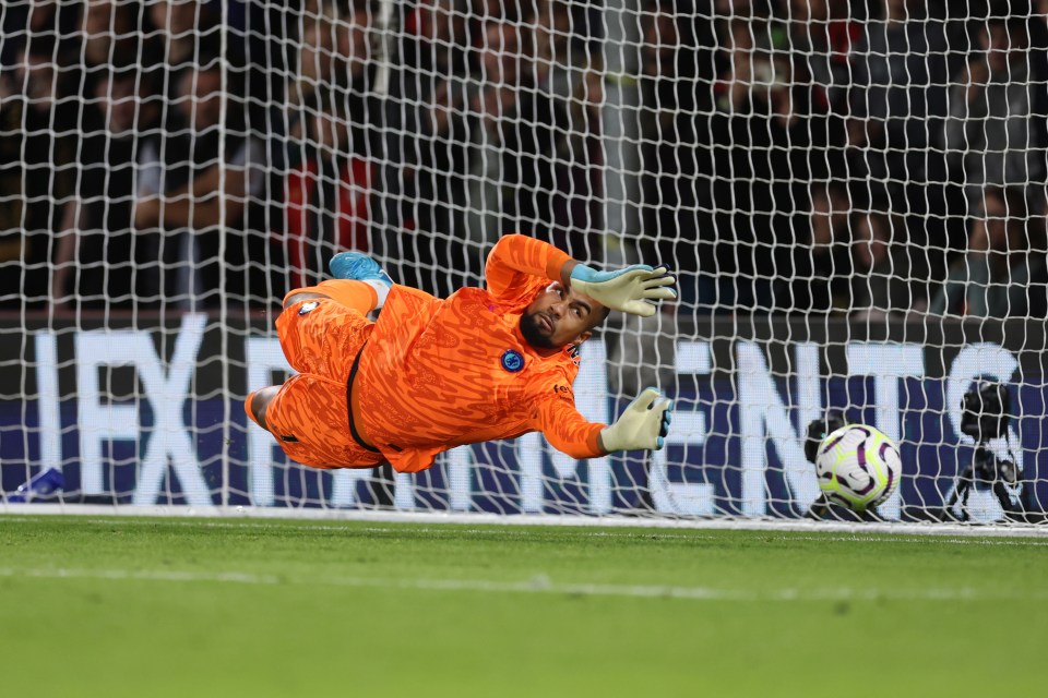 a soccer goalie dives to catch a ball in front of a sign that says exit