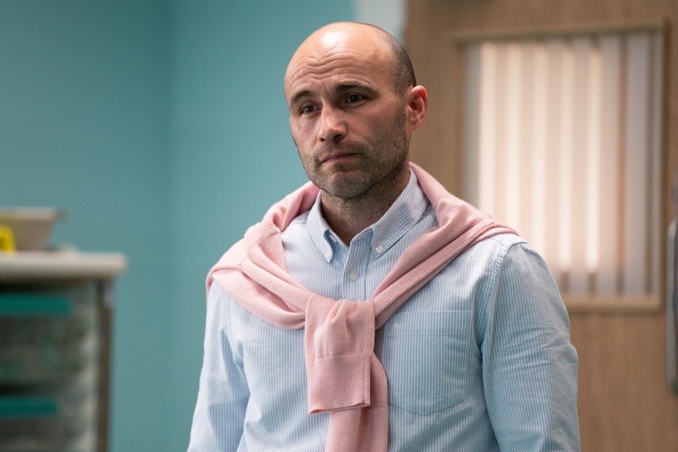 a bald man wearing a pink sweater around his neck