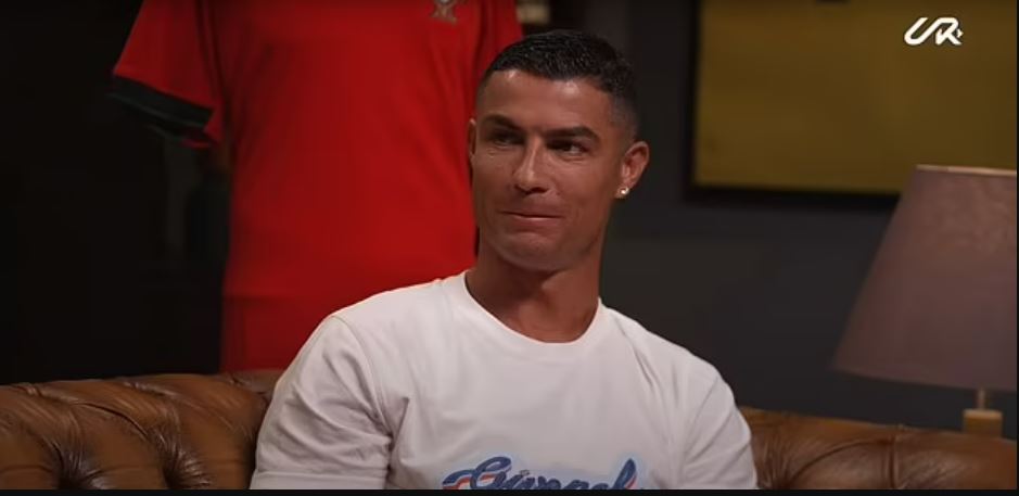 a man is sitting on a couch wearing a white t-shirt .