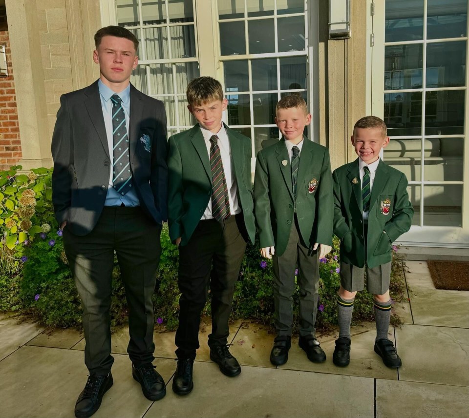 four boys in suits and ties stand in front of a building