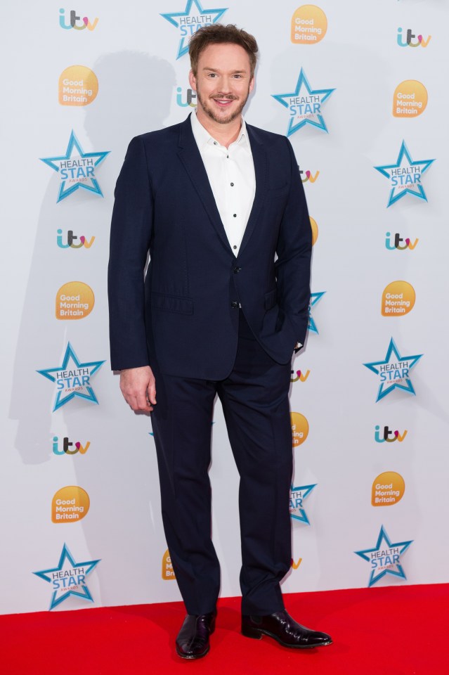 a man in a suit stands in front of a red carpet that says good morning britain