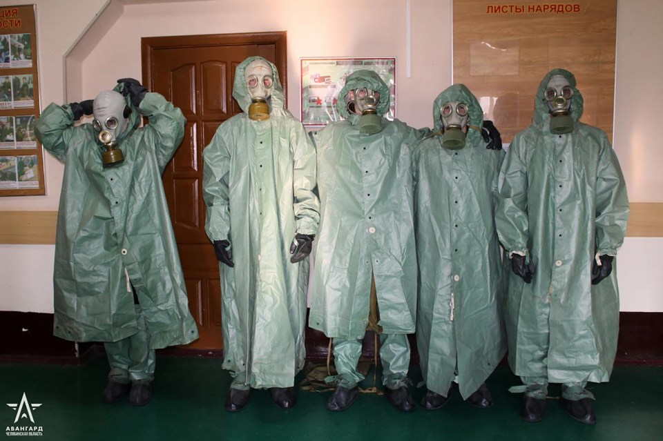 a man wearing a gas mask is standing in front of a poster that says " защита "