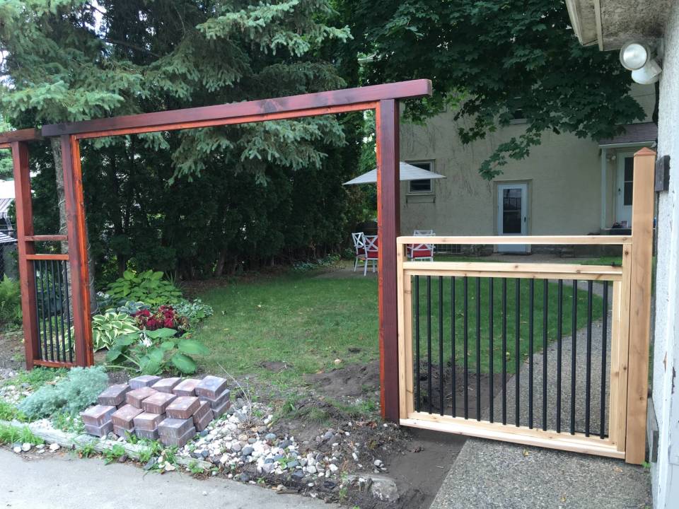 a wooden gate leading to a backyard with a white house in the background