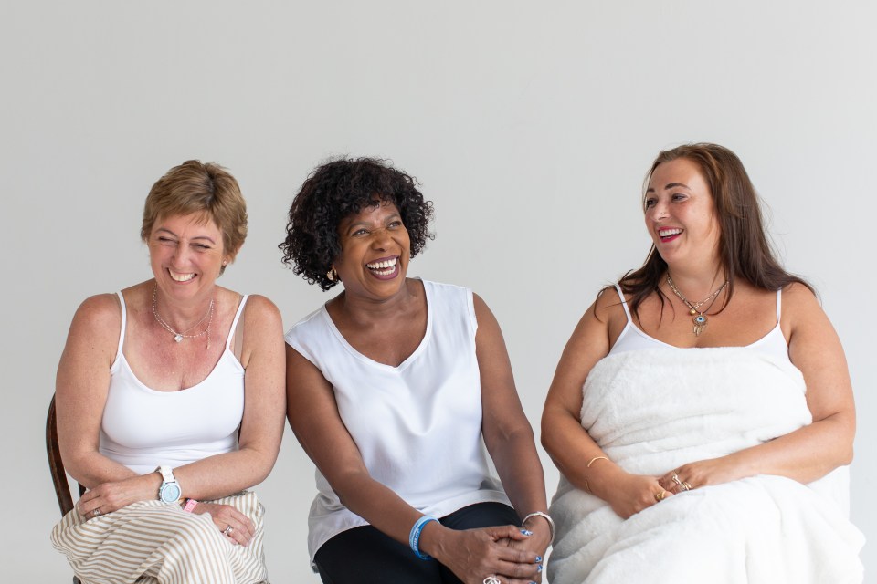 three women are sitting next to each other and laughing