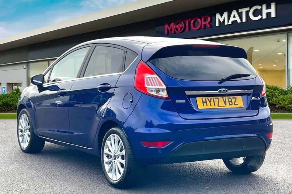 a blue ford car is parked in front of a motor match store