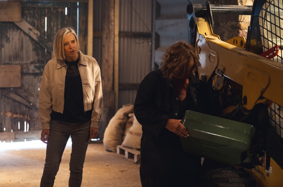 two women standing in front of a yellow bulldozer with a green box in front of it