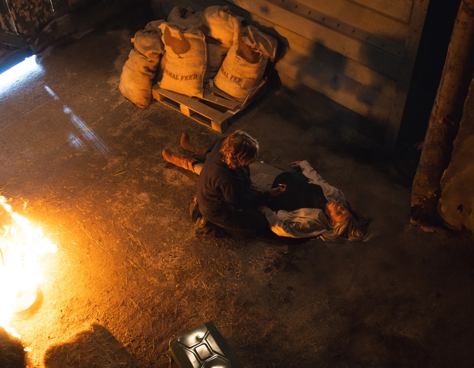 a person laying on the ground with bags of animal feed in the background