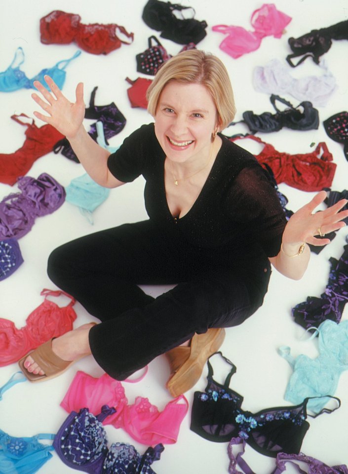 a woman is sitting on the floor surrounded by bras