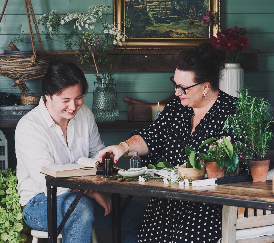 a man and a woman sit at a table looking at a book