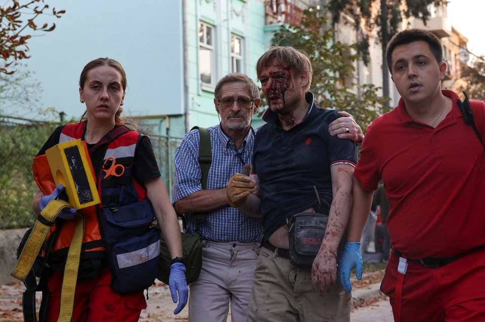 An injured man walks with paramedics after getting rescued from a residential building damaged during Russia's strike on Wednesday