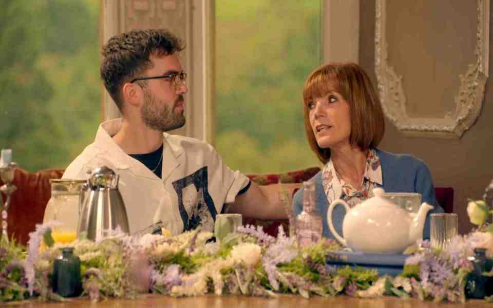 a man and woman sit at a table with flowers and a teapot