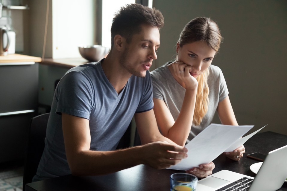 a man and a woman sit at a table looking at a piece of paper