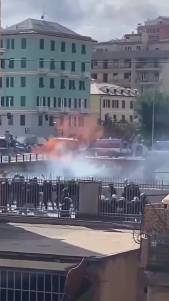 a group of people are standing in front of a building with smoke coming out of it