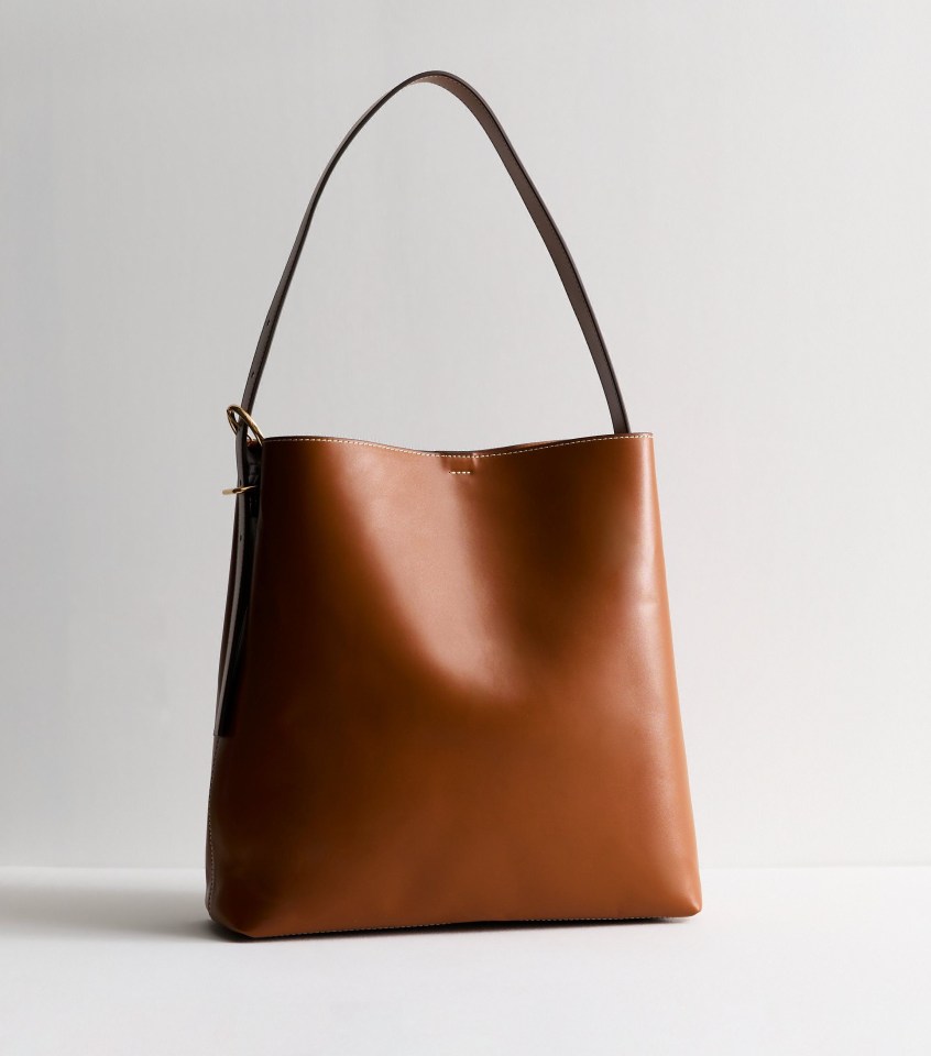 a brown leather bag with a brown strap on a white background