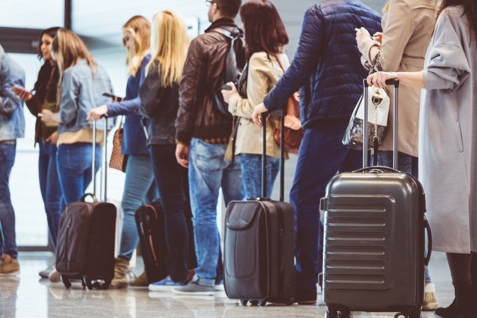 a group of people standing in a line with luggage