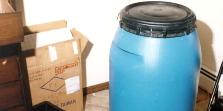 a blue barrel is sitting next to a cardboard box in a room .