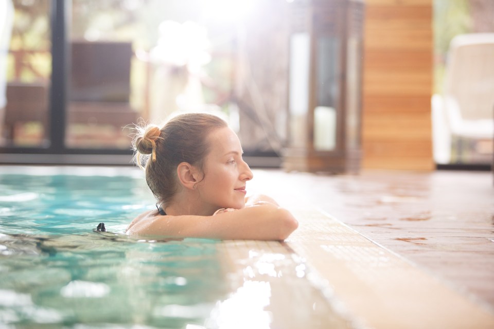 a woman is leaning on the edge of a swimming pool