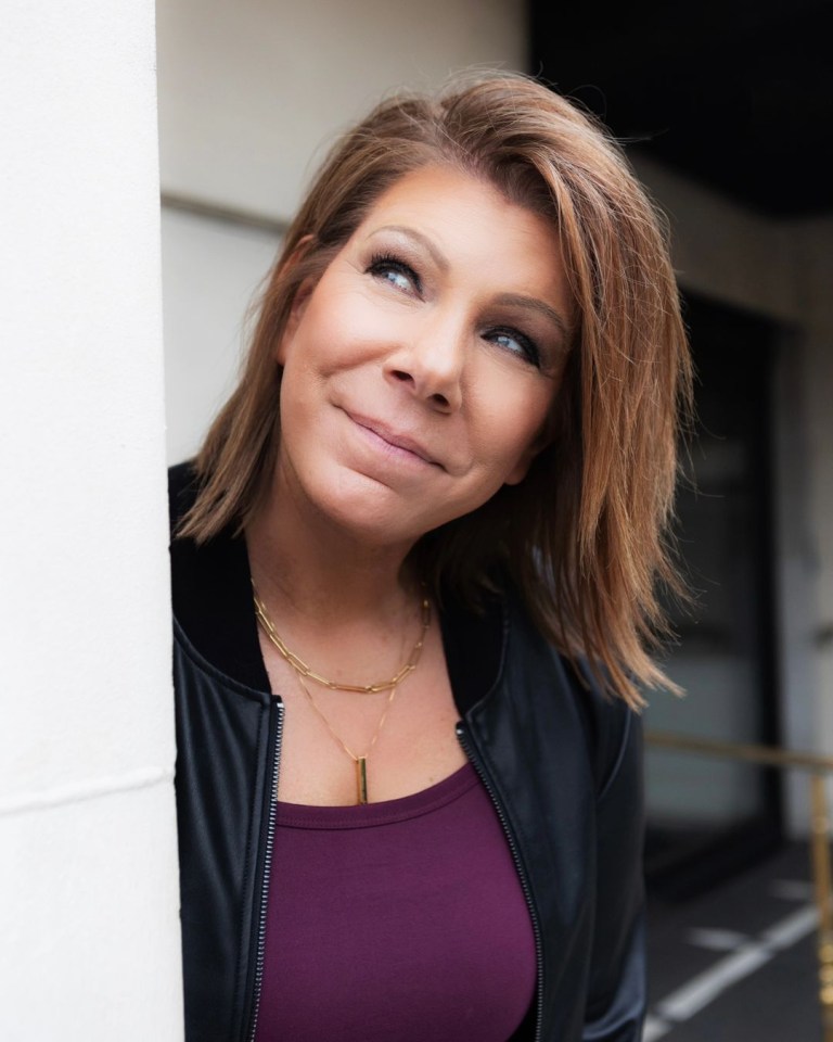 a woman leaning against a wall with a smile on her face