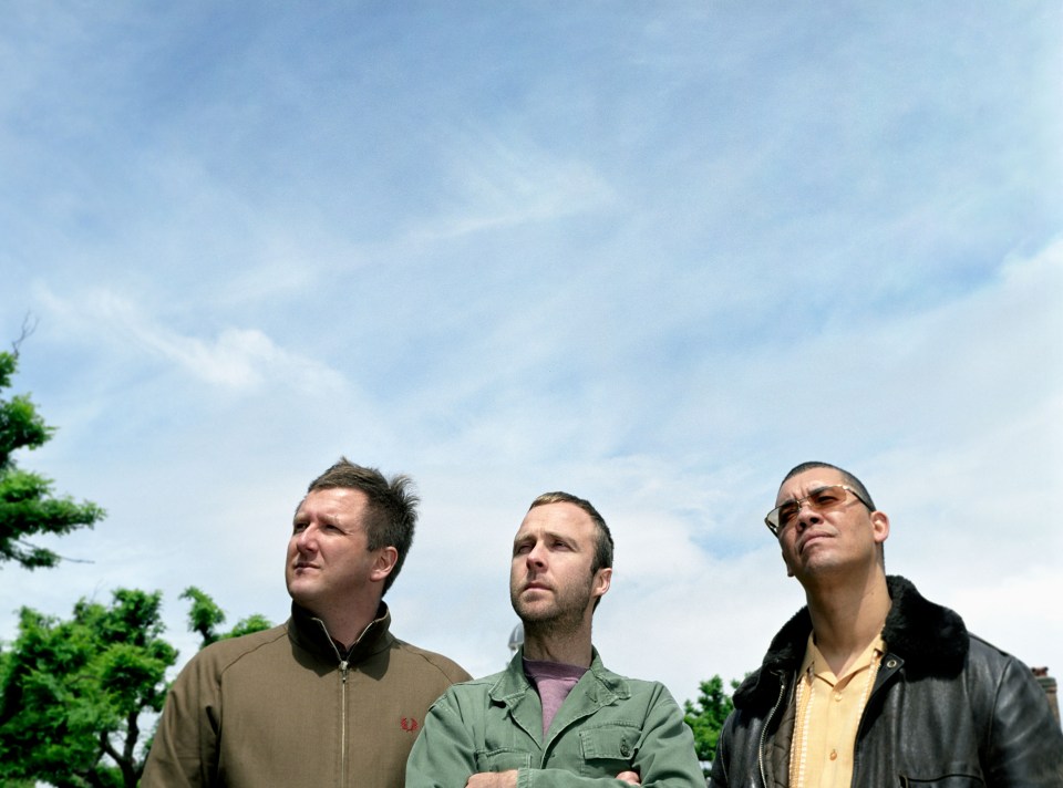 three men are standing in front of a blue sky