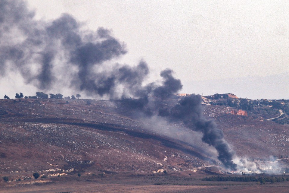 smoke coming out of a mountain with trees in the background