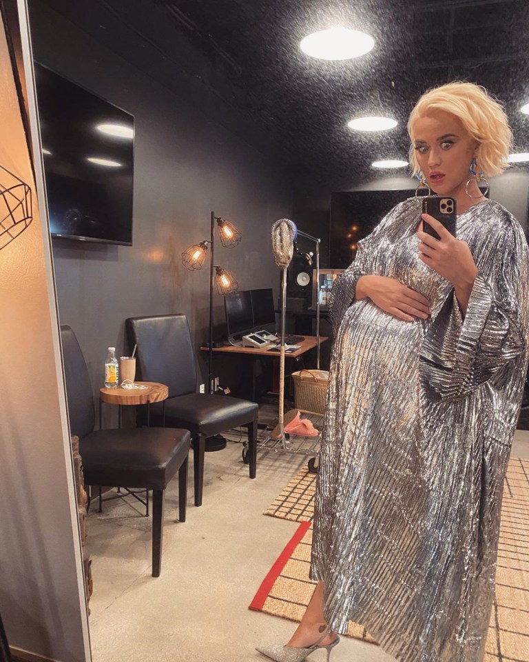 a woman in a silver dress takes a selfie in front of a mirror