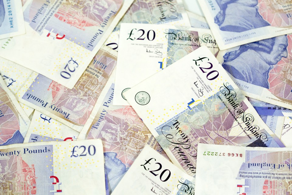 a pile of twenty pound notes are spread out on a table