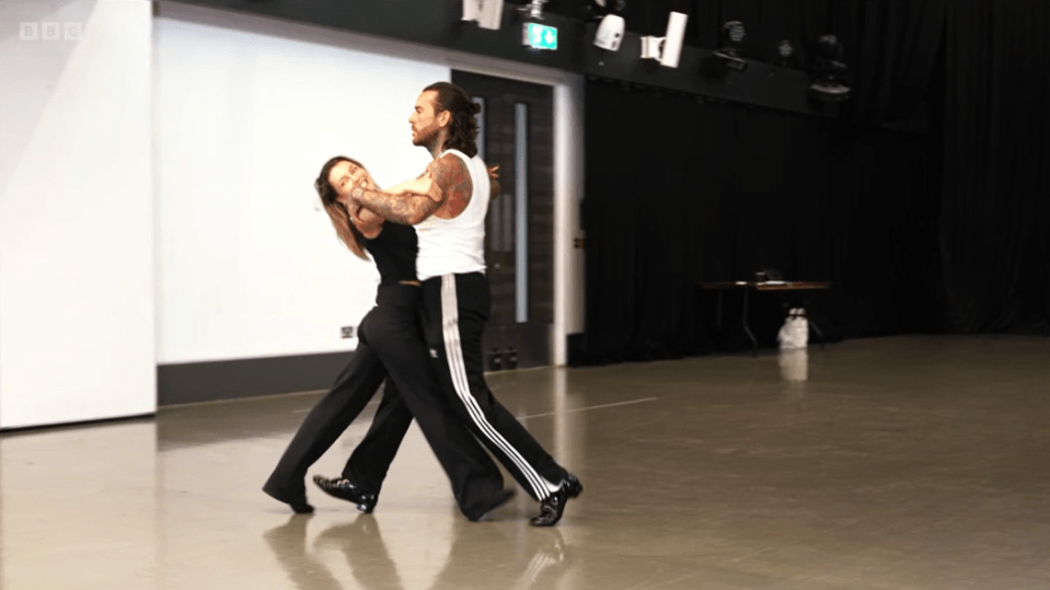 a man and a woman are dancing in front of a bbc sign