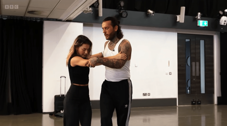 a man and a woman are dancing in a room with bbc written on the ceiling