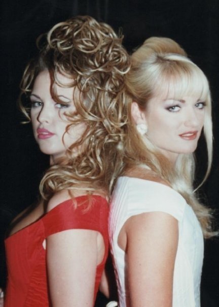 two women are standing back to back and one is wearing a red dress