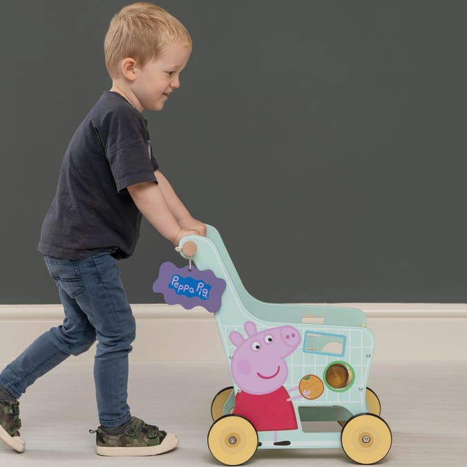 a little boy pushes a peppa pig shopping cart