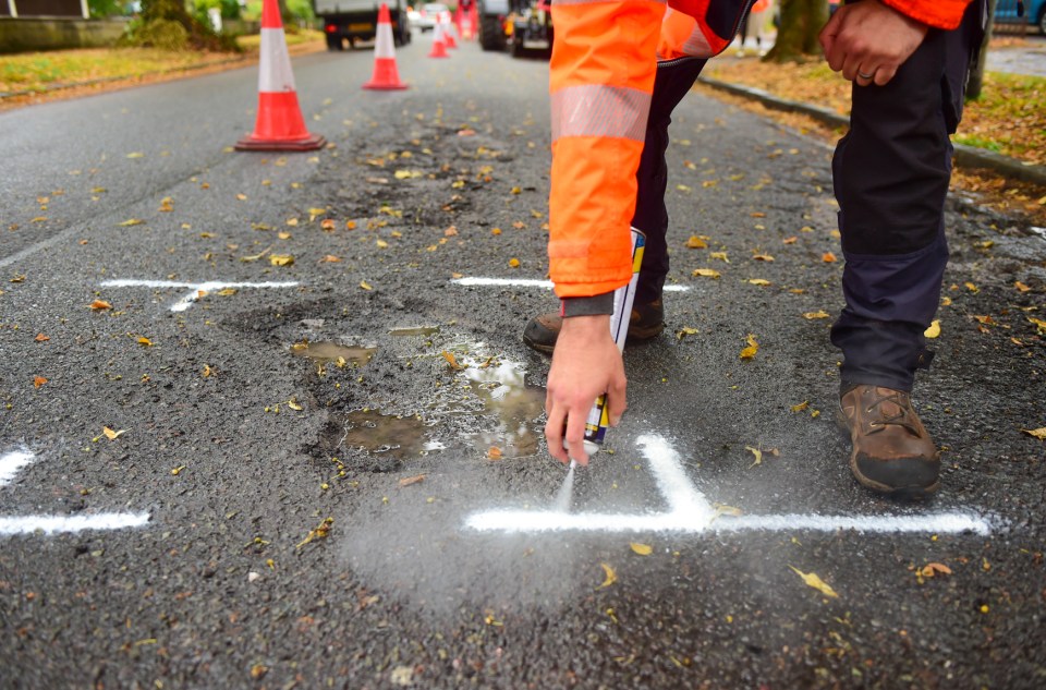 Road worker uses spray paint to mark problem area