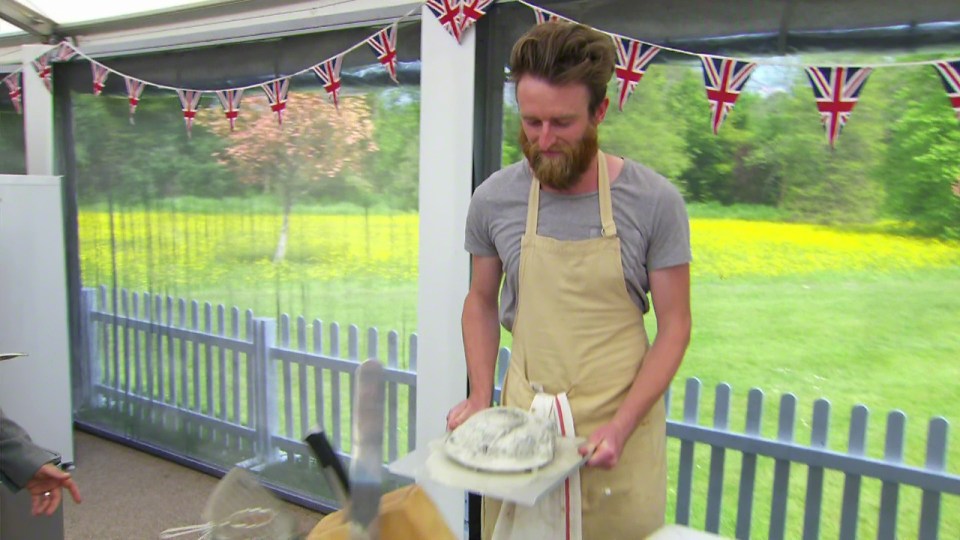 a man in an apron is holding a piece of cake