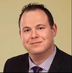 a man in a suit and tie is smiling for the camera .