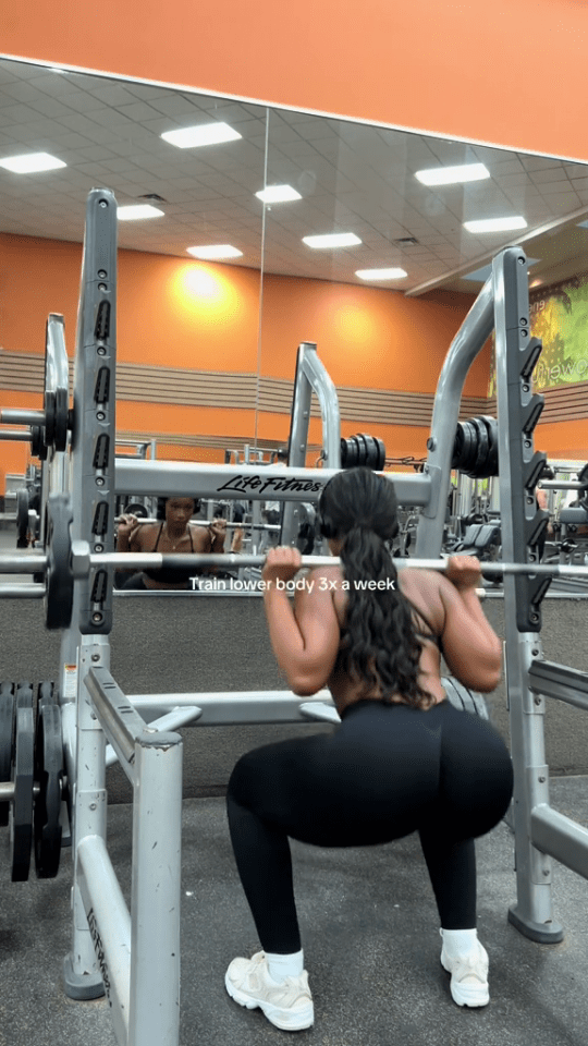 a woman squatting in front of a life fitness machine