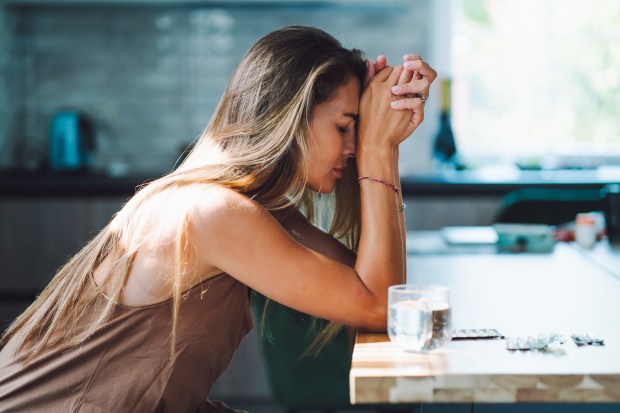 a woman sits at a table with her head in her hands