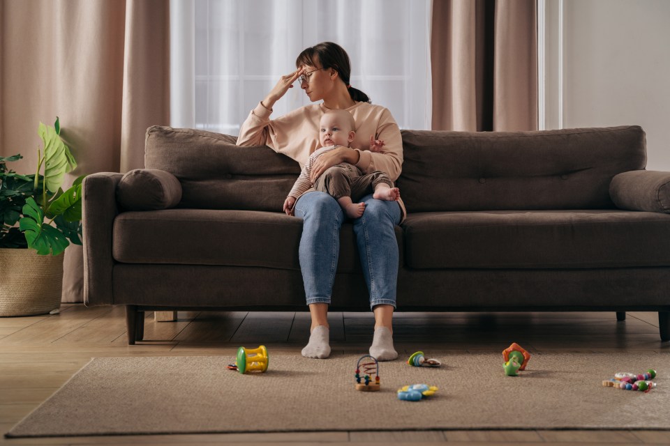 a woman sits on a couch holding a baby