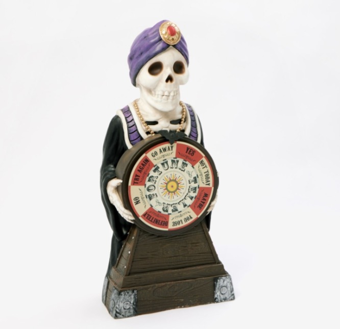 a statue of a skeleton holding a fortune wheel