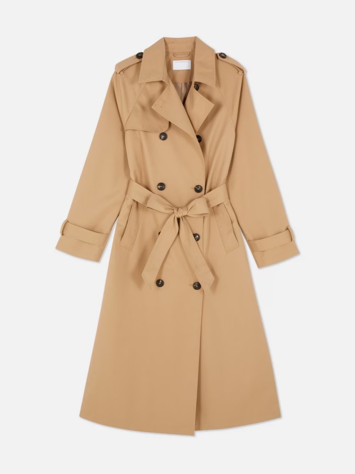 a tan trench coat with black buttons and a belt