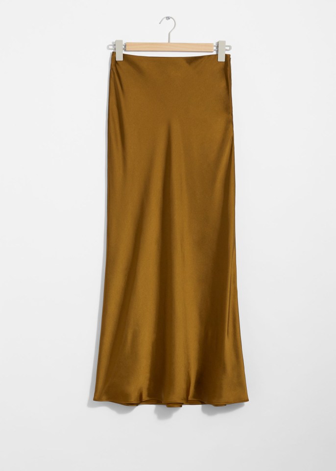 a brown satin skirt is hanging on a wooden hanger