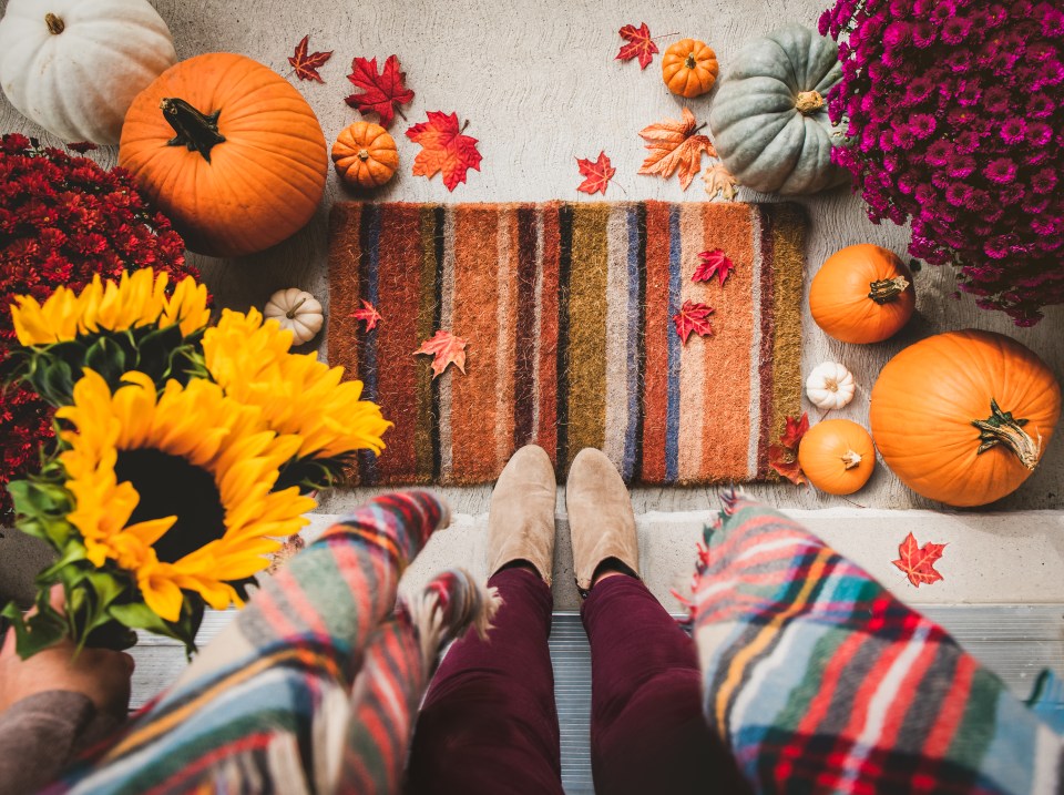 a couple sitting on a porch surrounded by pumpkins and flowers