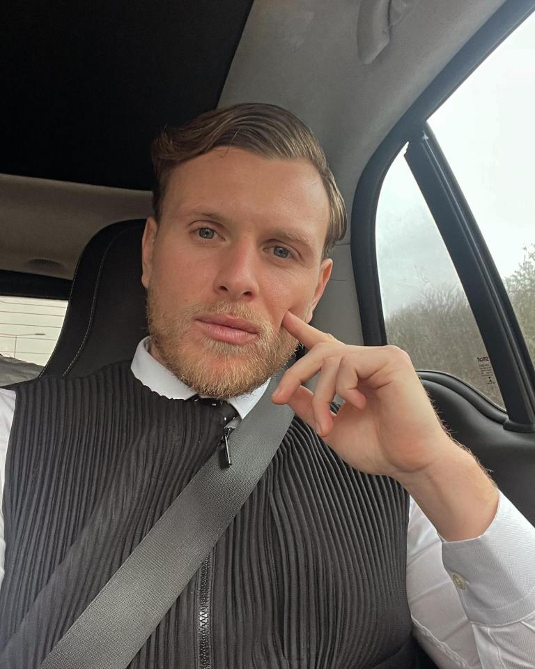 a man sitting in a car with his hand on his chin