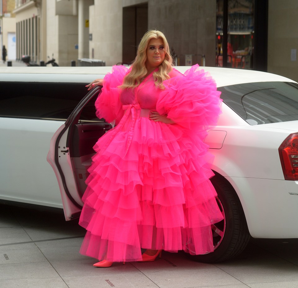 a woman in a bright pink dress stands next to a white limousine